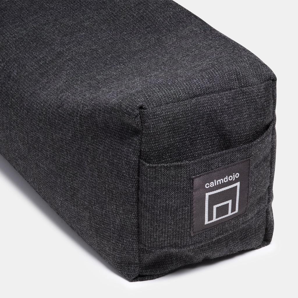 closeup of bolster face with carrying handle and woven logo label against a white background.