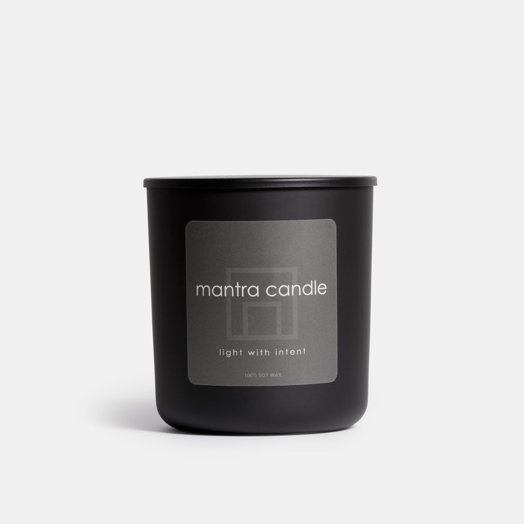Mantra candle in black glass jar with gray label.
