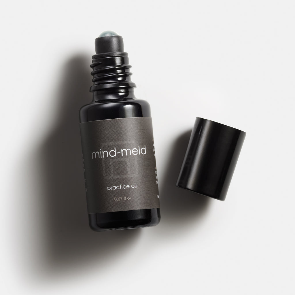Open black bottle of mind-meld practice oil with roller ball visible and cap to the side.