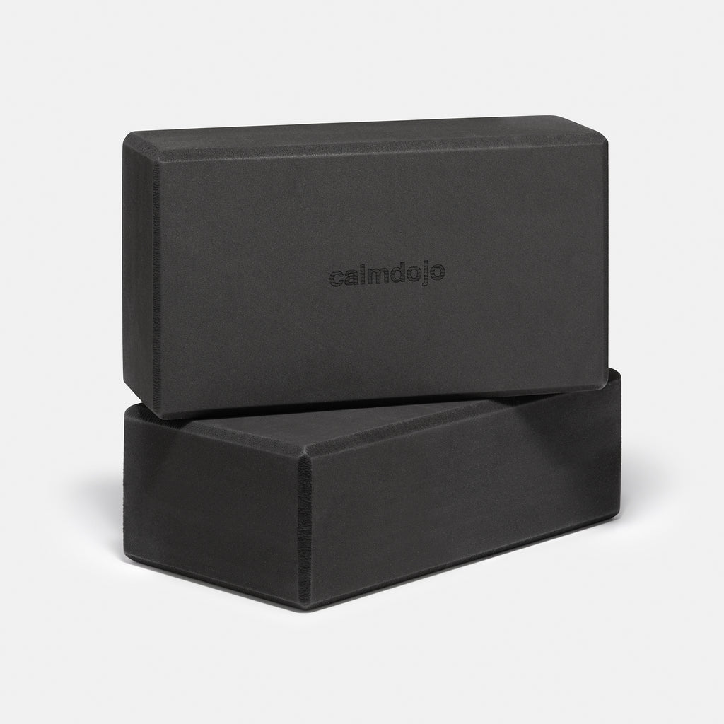 two black yoga blocks with calmdojo logo visible stacked on top of each other.