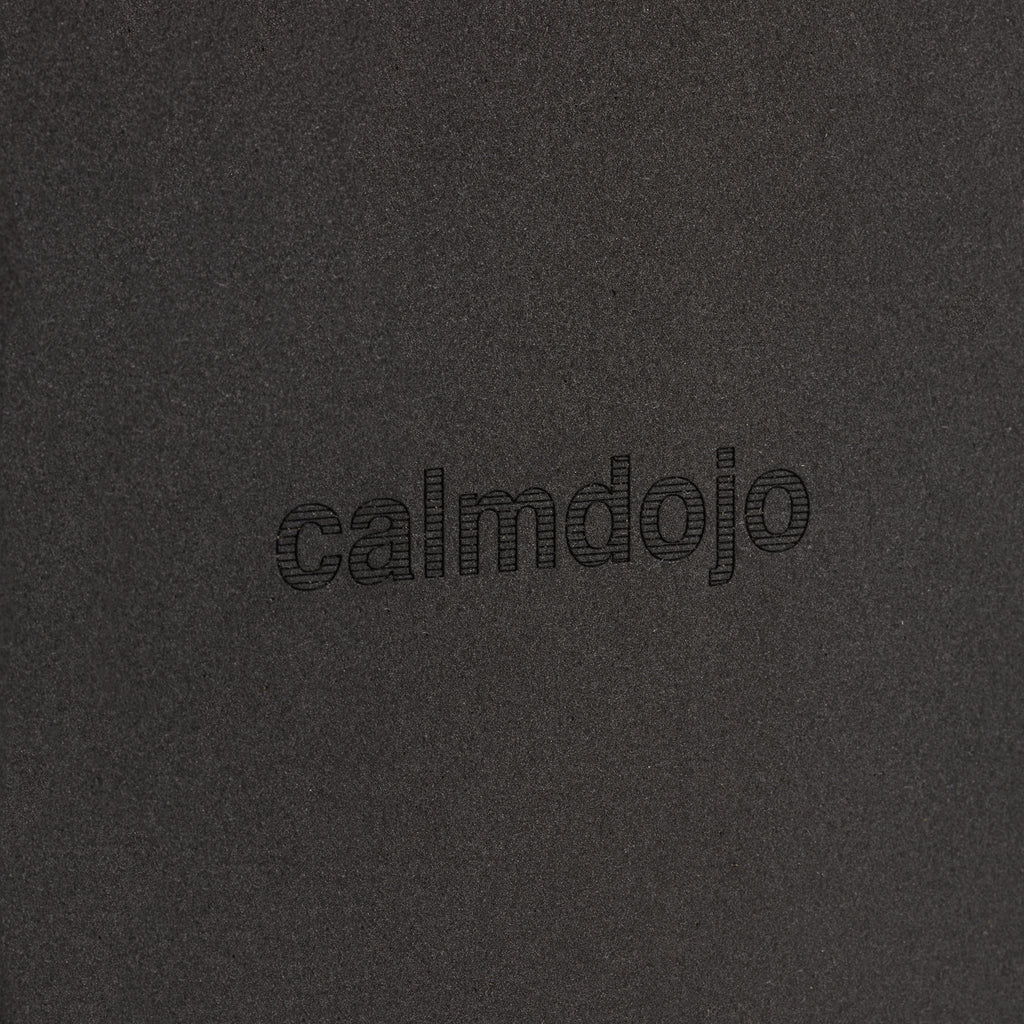 close up of laser engraved calmdojo logo on block surface.