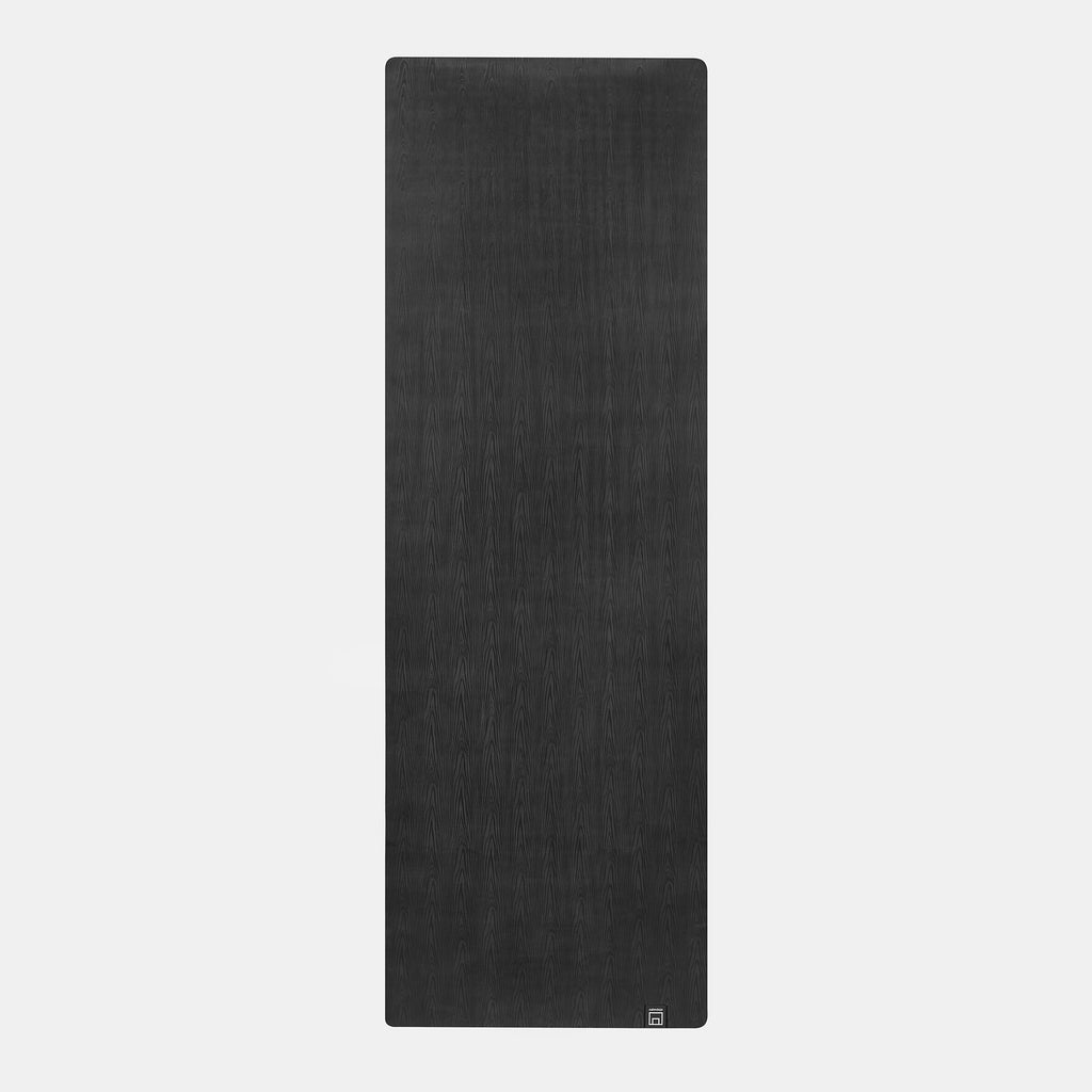 full length image of dark gray yoga mat with wood grain textured surface.
