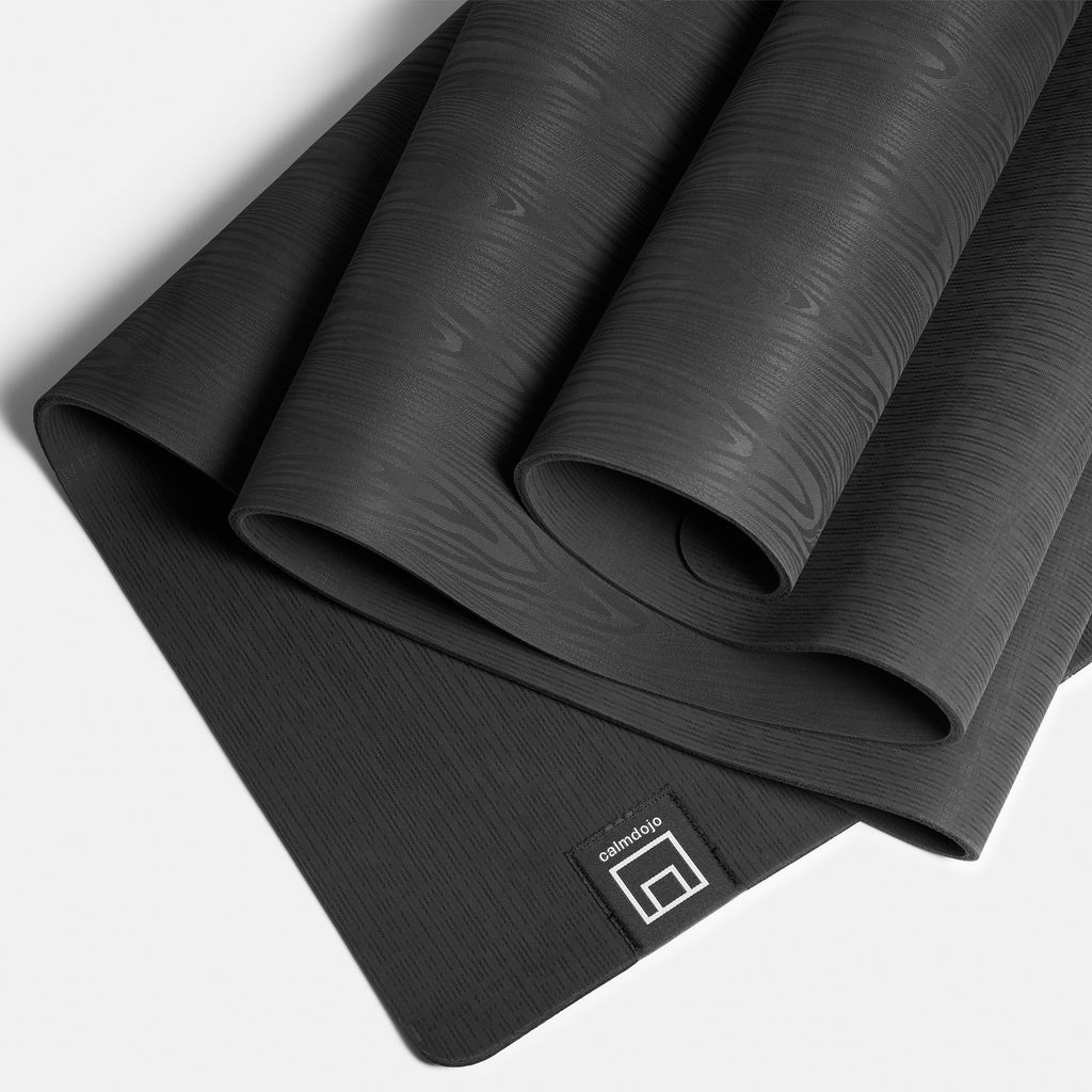 Softly folded dark gray yoga mat with wood grained textured surface