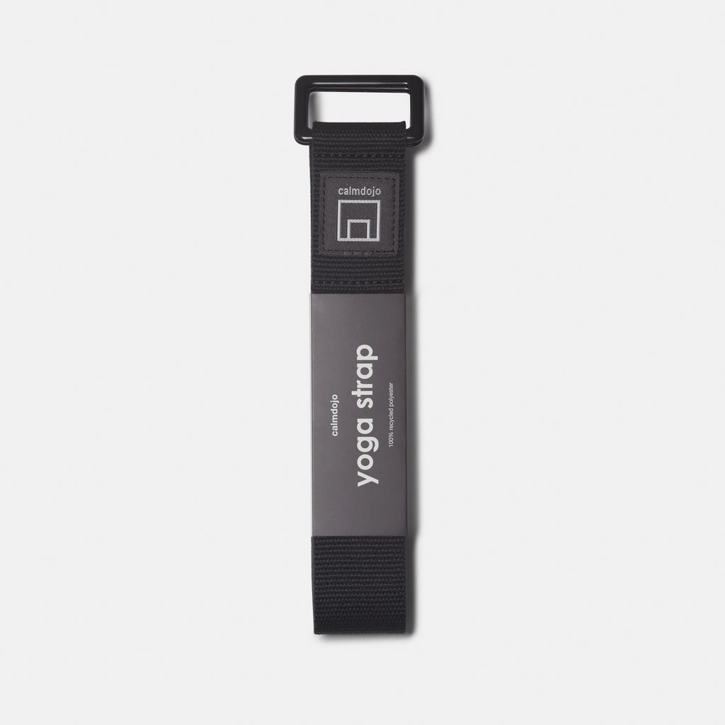 verticle view of black yoga strap with calmdojo logo and gray packaging labe.