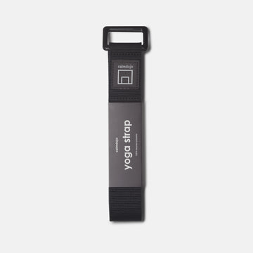 verticle view of black yoga strap with calmdojo logo and gray packaging labe.