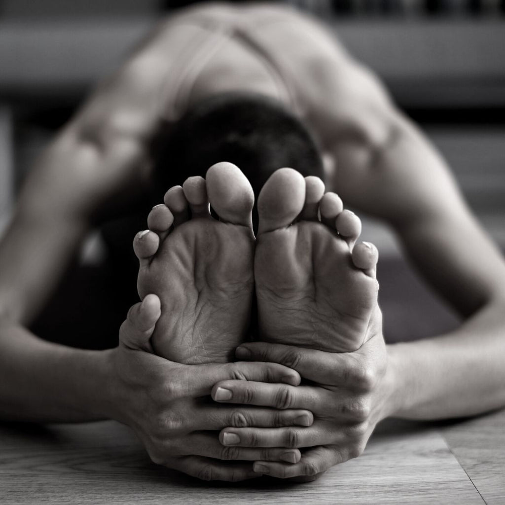 woman in forward fold clasping her feet with her hands